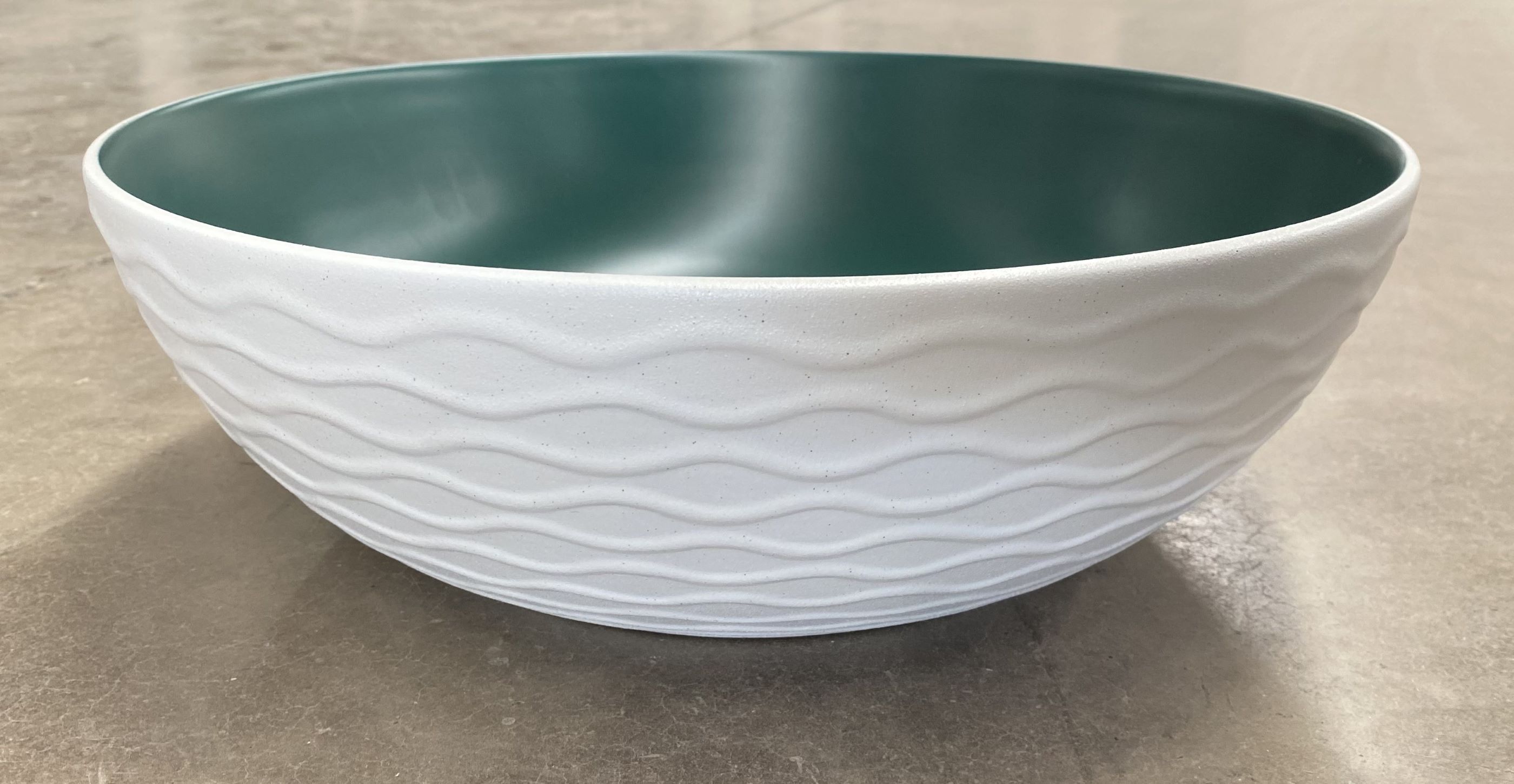 Lavabo Cerámico para Baño KAU, forma redonda color en el exterior blanco mate con textura en alto relieve y acabado rústico, esmalte verde en el interior. De sobreponer con diseño europeo ideal para todo tipo de baños. Dimensiones 400x400x135 mm